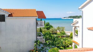 Une vue sur la côte, avec un bâtiment blanc, un toit recouvert de tuiles rouges et un balcon donnant sur la mer.