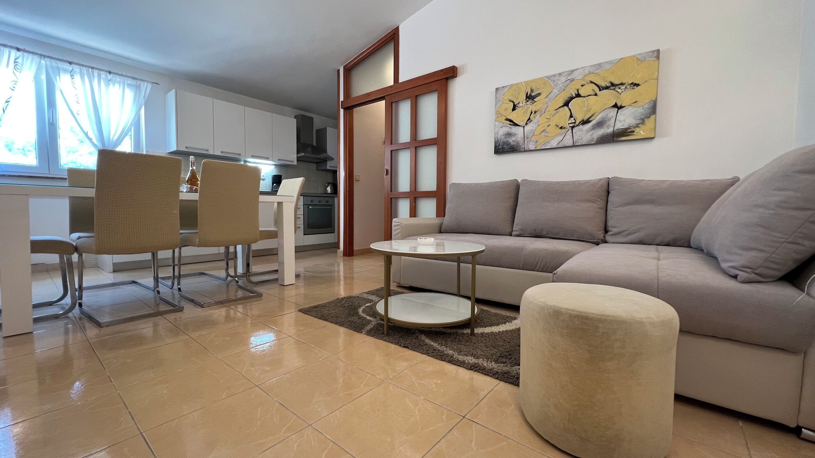 A modern living room with a sofa, a round coffee table, and a dining area with chairs.