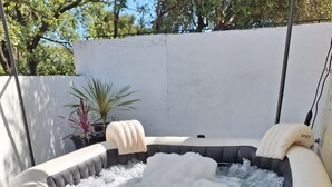 Ein aufblasbarer Whirlpool mit Kissen, ein Tisch mit Getränken und Handtüchern, sowie eine kleine Schale mit Snacks.
