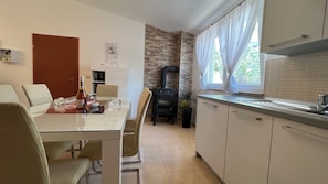 A modern kitchen with a dining area, featuring a stove, cabinets, and a dining table with chairs. - House Roca With Jacuzzi (Vodice)