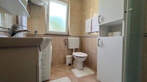 Ein kleines, sauberes Badezimmer mit Toilette, Waschbecken und Fenster.