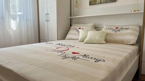 Een net opgemaakt bed met een sprei waarop staat: 'The Righteous Way' en 'I Love My Father Always'.