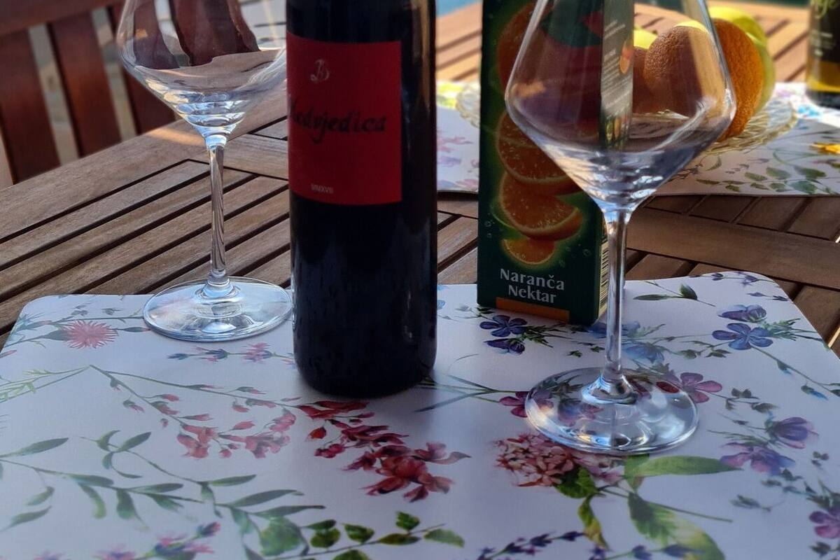 A bottle of Narancha Nectar wine, a glass, and a box of Juicy Narancha Nectar on a table with a floral tablecloth.