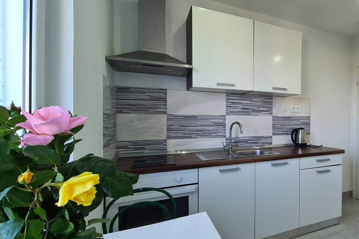 A modern kitchen with white cabinets, a stainless steel sink, and a built-in stove.