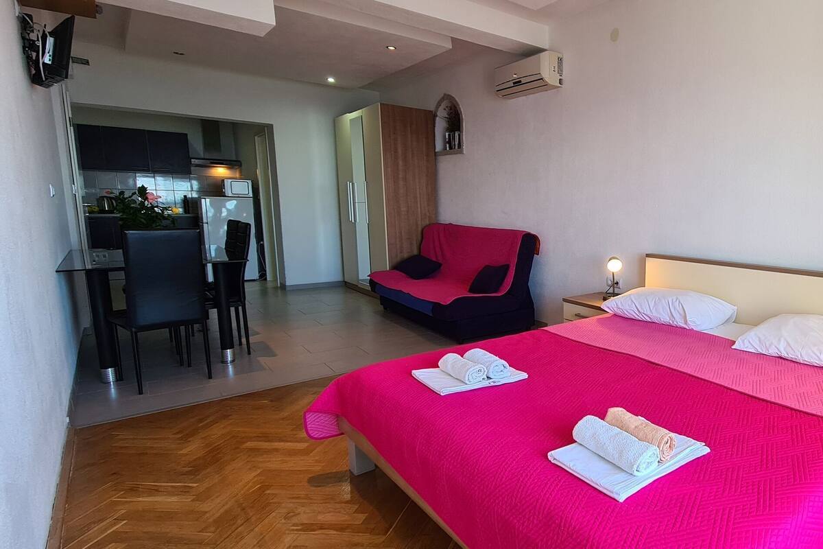 A bedroom with a large bed, a bedside table with a lamp, and a chair.