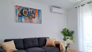 A modern living room with a grey sectional sofa, a wooden coffee table, and a potted plant. - Apartment Beach View (Crikvenica)