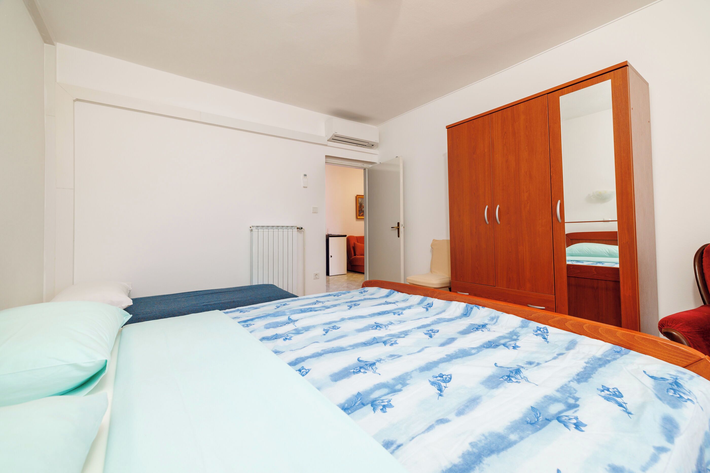 Ein Schlafzimmer mit Bett, Kleiderschrank und Heizkörper.