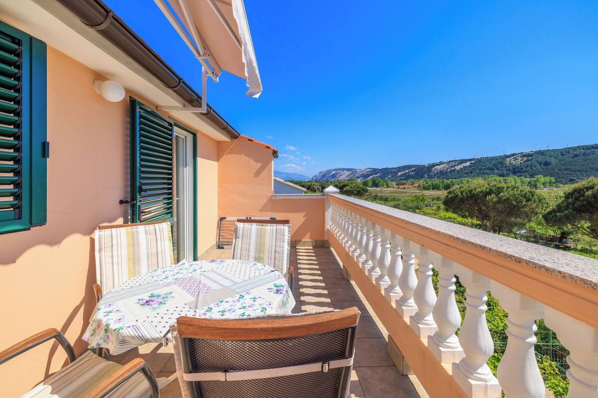 Ein Balkon mit Tisch und Stühlen, Blick auf die Landschaft und einem weißen Geländer.