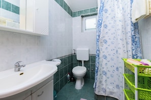 Ein Badezimmer mit einem weißen Waschbecken, einer Toilette und einer Duschvorhang mit blauem Muster.
