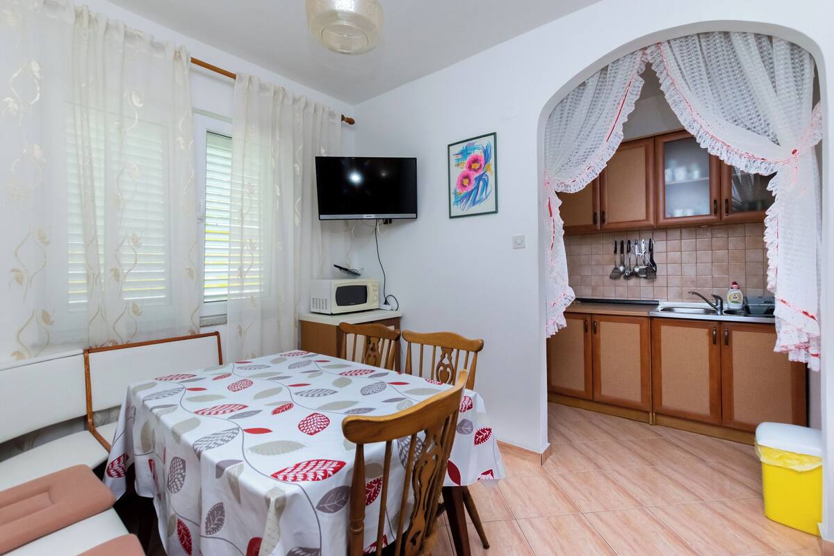 A compact kitchen with a dining area, a TV, and a microwave.