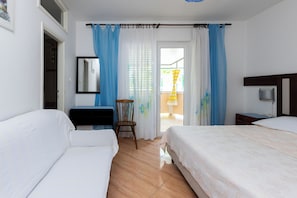 Ein Hotelzimmer mit zwei Betten, einem Schreibtisch, einem Stuhl und einem Vorhangfenster.