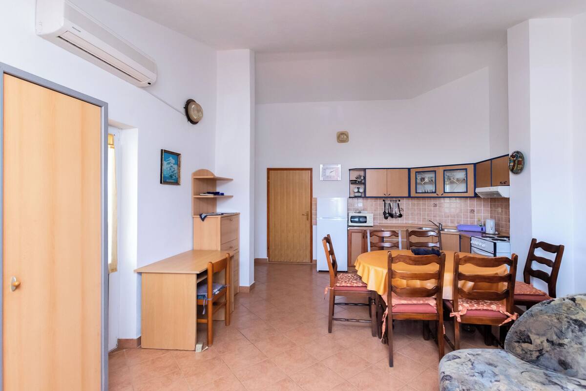 A compact kitchen with a dining area, wooden furniture, and a built-in oven.