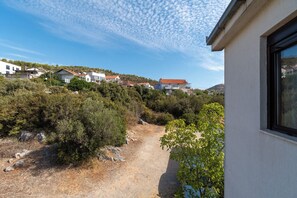 A residential area with houses on a hillside, a dirt path, and a building with a window. - Apartments Mirjana (Marina)