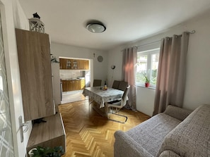 Ein kompakter Wohnbereich mit Essplatz, Küchenzeile und einem Vorhangfenster.