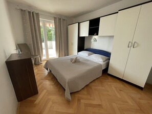 Quarto com cama, escrivaninha, guarda-roupa e janela com cortinas.
