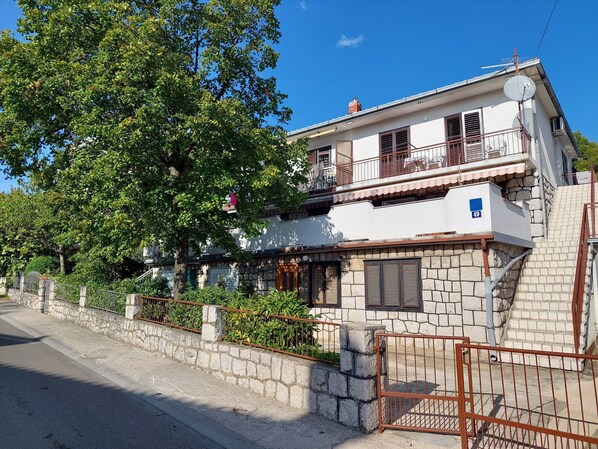 Une maison à deux étages avec une façade en pierre, un balcon et une antenne parabolique.