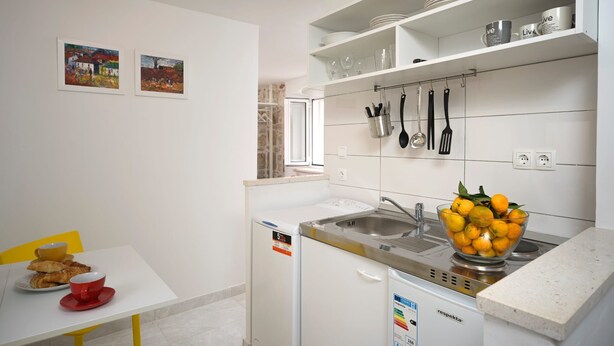 A modern kitchen with white cabinetry, a sink, and a bowl of lemons on the counter. - Apartments Lotti 2 (Stari Grad)