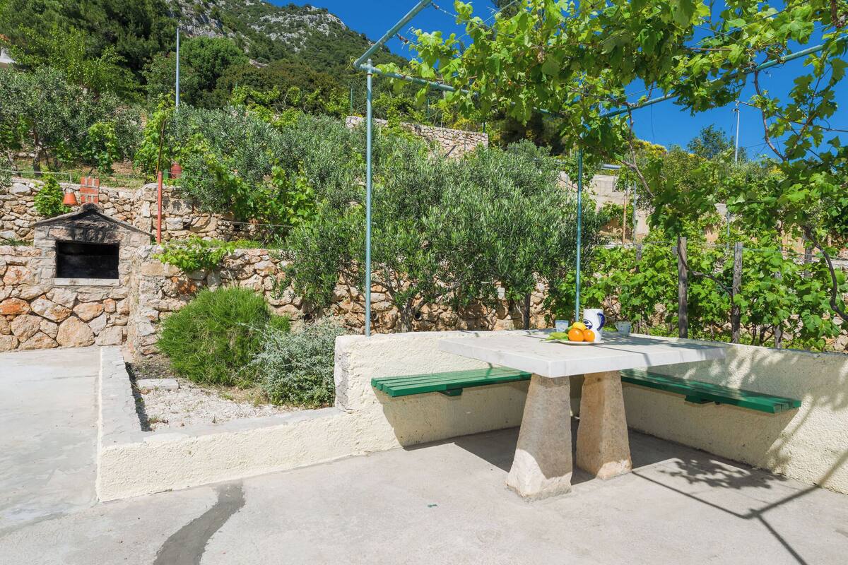 Un espace extérieur aménagé avec un mur en pierre, une table et un banc.