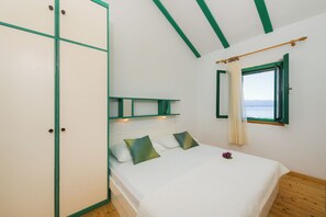 Una camera da letto con un letto, un armadio, una finestra con tende e vista mare.