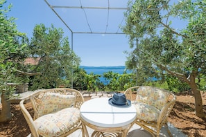 A wicker table and chairs set up under a pergola with a view of the sea and mountains. - Apartments Nada (Bol)
