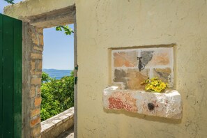Un muro in pietra con una piccola nicchia che ospita un'icona religiosa e fiori.