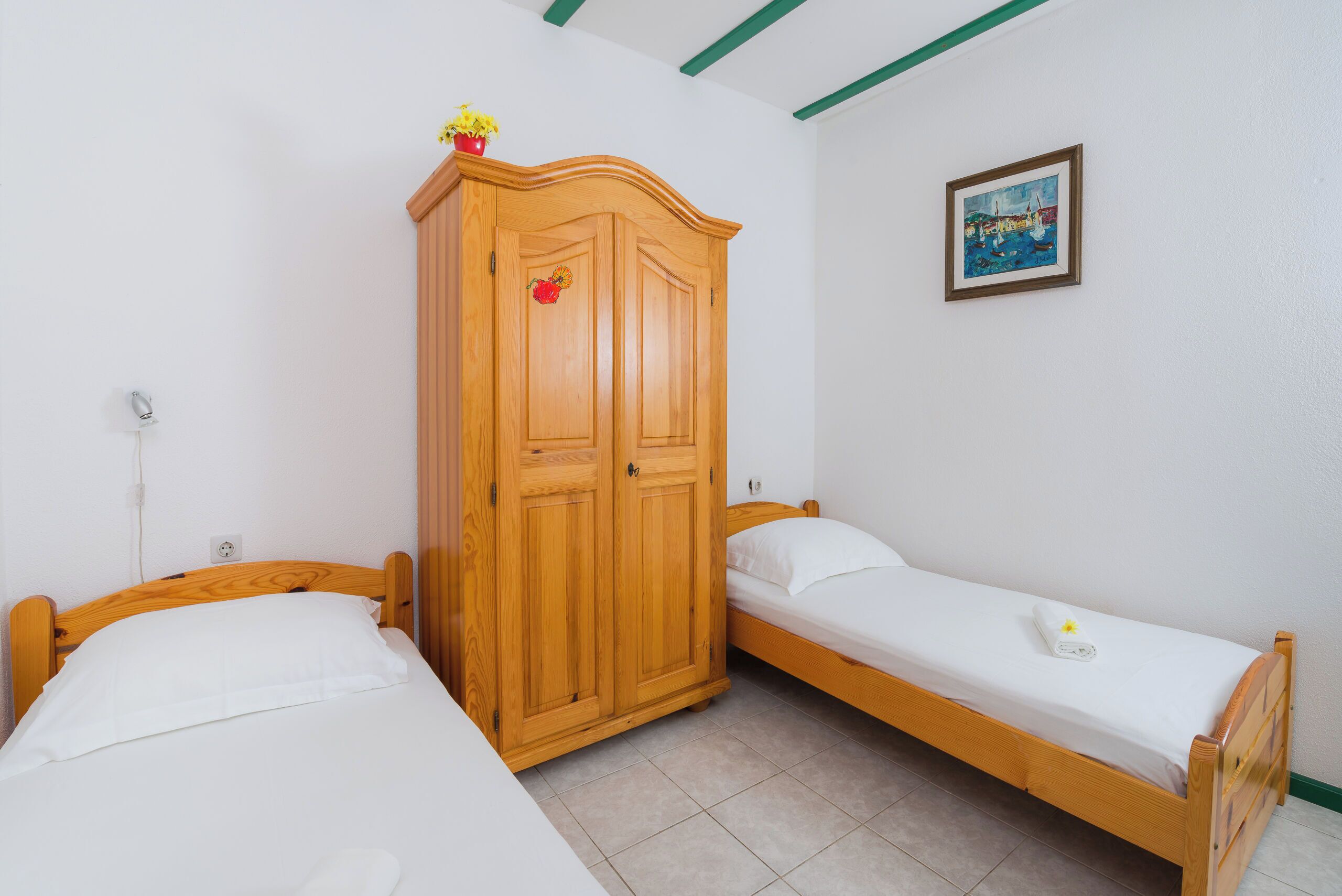 Una stanza con due letti di legno, un armadio e un quadro appeso al muro.