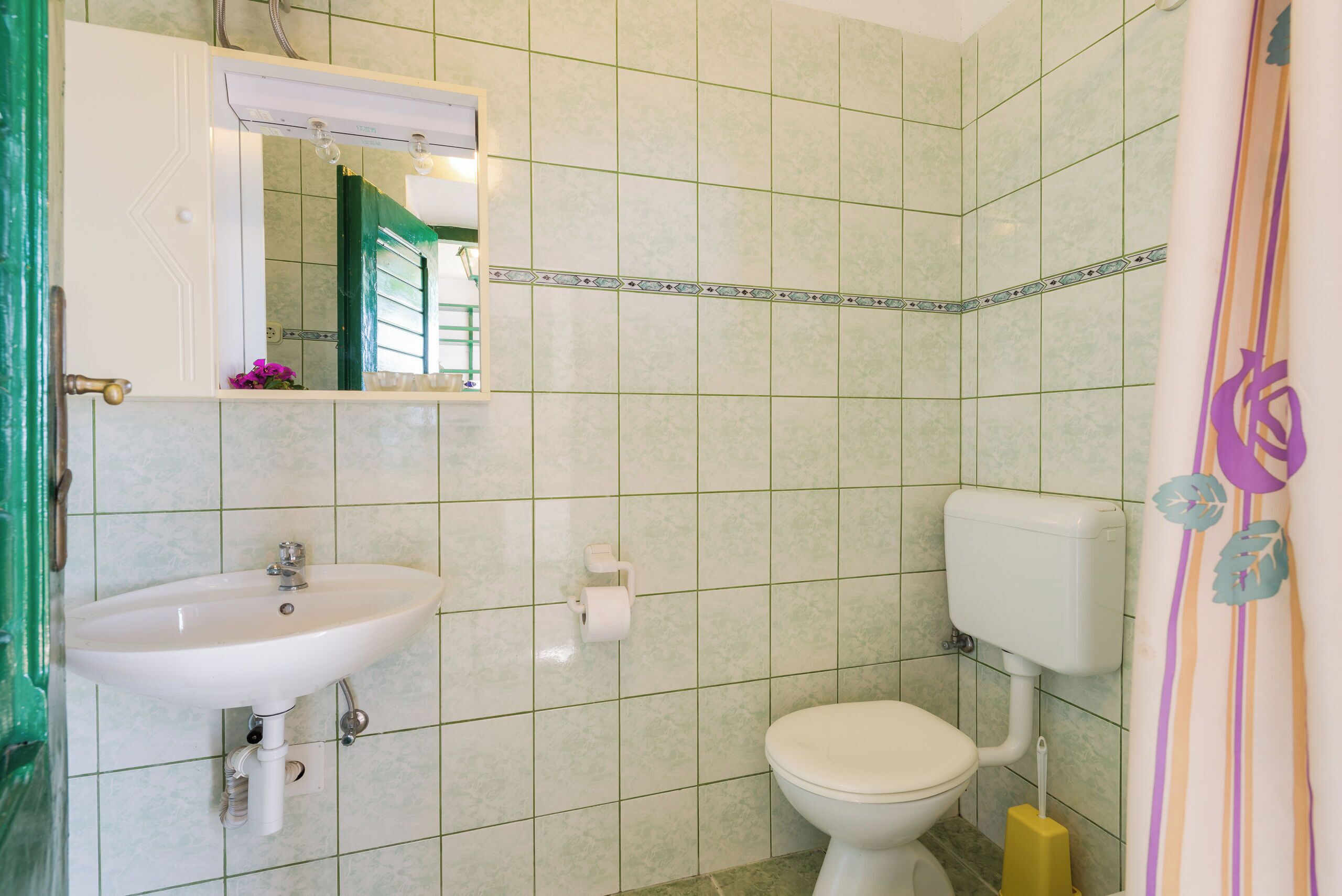 Ein Badezimmer mit Waschbecken, Toilette und Spiegel.