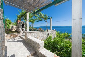 Una scala in pietra conduce a un'area esterna coperta con vista sul mare.