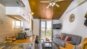A compact living space with a kitchenette, a sofa, a dining table, and a balcony with a view. - Apartment Sasa (Kastela)