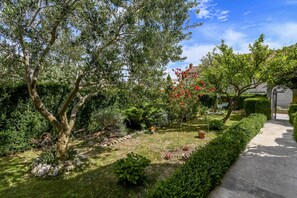 A well-maintained garden with a variety of plants and a paved walkway. - Apartment Sasa (Kastela)