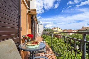 A balcony with a table, a vase with red flowers, and a basket of cherries. - Apartment Sasa (Kastela)