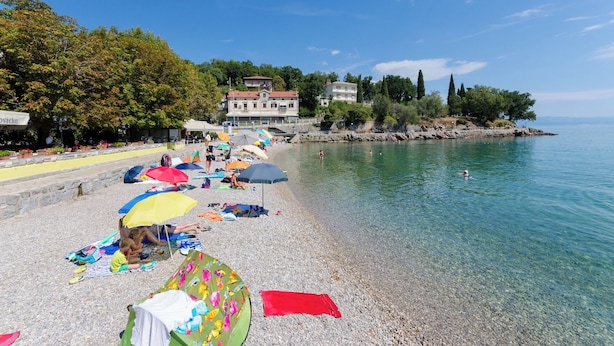 Une plage de galets avec des parasols et des gens qui se détendent.