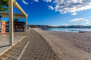 A beachside walkway with a kiosk and a view of the sea and town in the background. - House Little Flower 1 (Okrug)