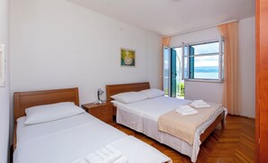Une chambre d’hôtel avec deux lits, une table de chevet avec une lampe, une fenêtre donnant sur un beau paysage et un tableau au mur.
