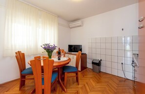 Un coin repas avec une table en bois, des chaises et un vase rempli de fleurs violettes.