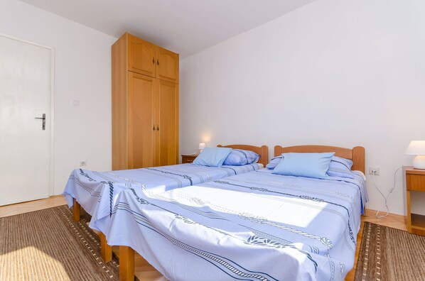 Une chambre à coucher avec un lit, une armoire en bois, une table de chevet et une lampe.