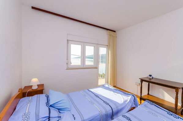 A bedroom with a bed, bedside table, lamp, and a window with curtains. - Apartment Ma (Marina)
