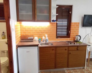 Une cuisine de taille réduite, équipée d’un réfrigérateur, d’un évier et de meubles de rangement en bois.