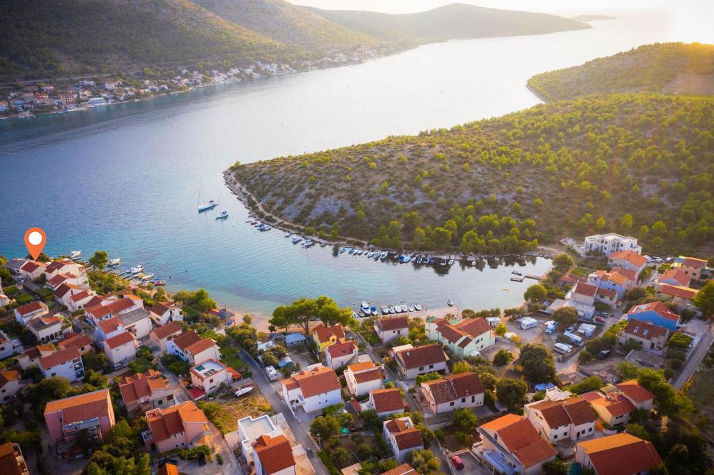 An aerial view of a coastal village with houses, a marina, and a bay.