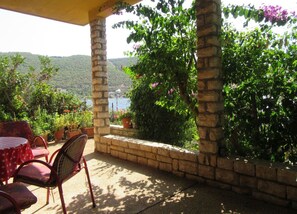 A covered patio with stone pillars, outdoor furniture, and potted plants. - Apartments Mala Kuca Kraj Mora (Sibenik)
