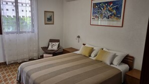 A hotel room with a bed, a chair, a nightstand, a wall-mounted lamp, and a painting. - Apartments Mala Kuca Kraj Mora (Sibenik)