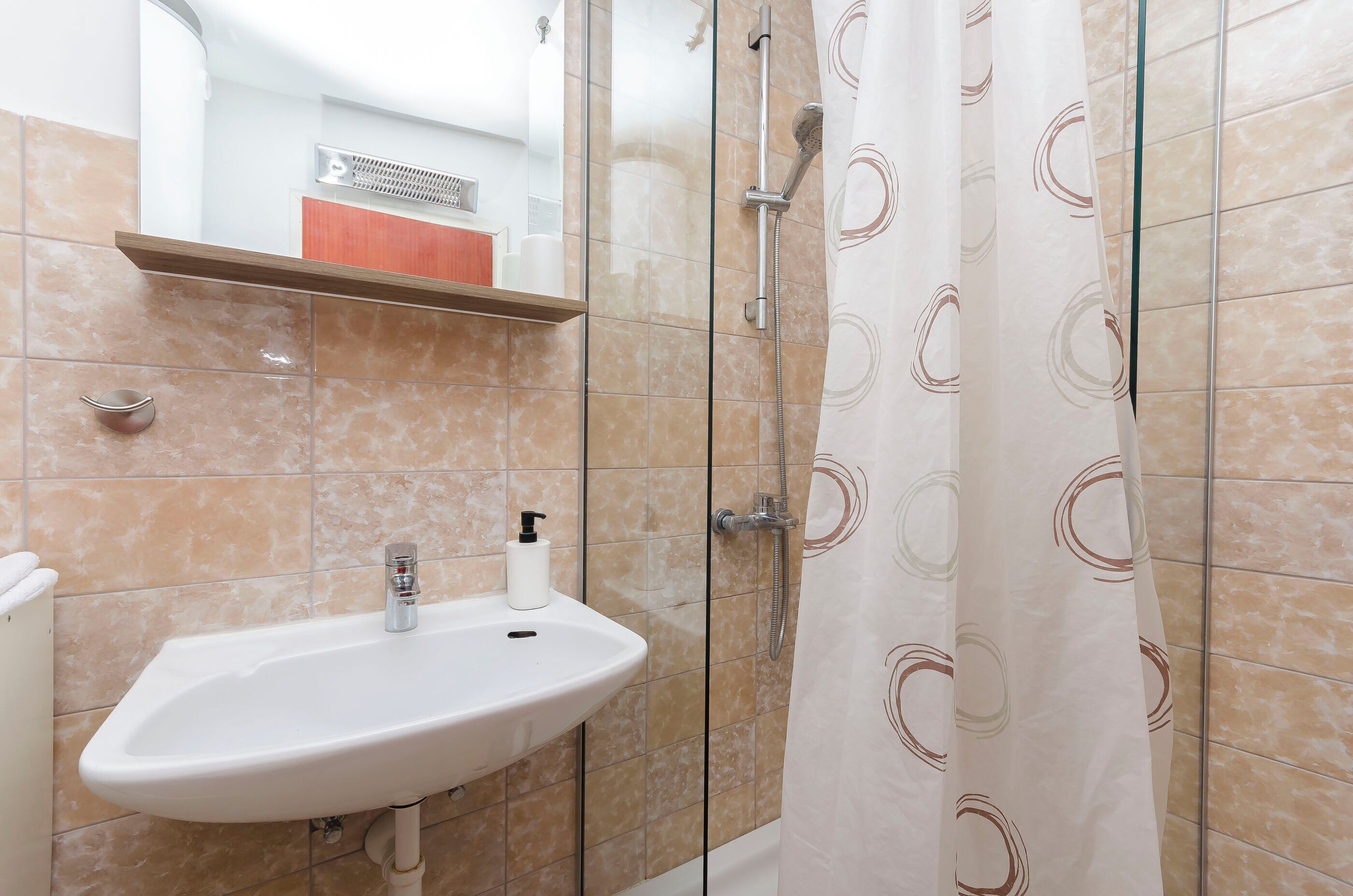 Een badkamer met een wastafel, douche en handdoekhouder.