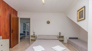 Ein Schlafzimmer mit einem Bett, einem Nachttisch, einem Kleiderschrank und einer Tür.
