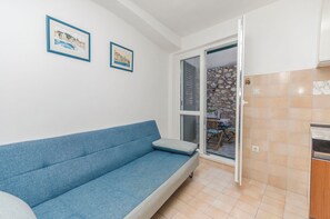 A room with a blue sofa, two framed pictures on the wall, a sliding glass door to a balcony, and tiled flooring. - Apartments Nautical Nest (Tribunj)