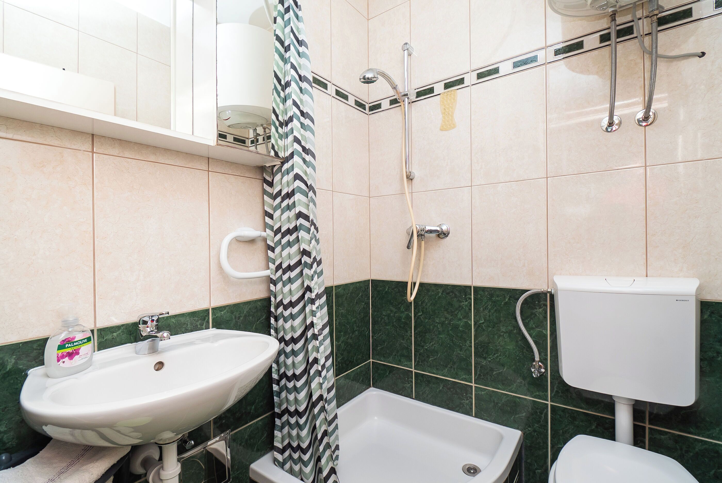 Un baño con lavamanos, inodoro, ducha y toallero.