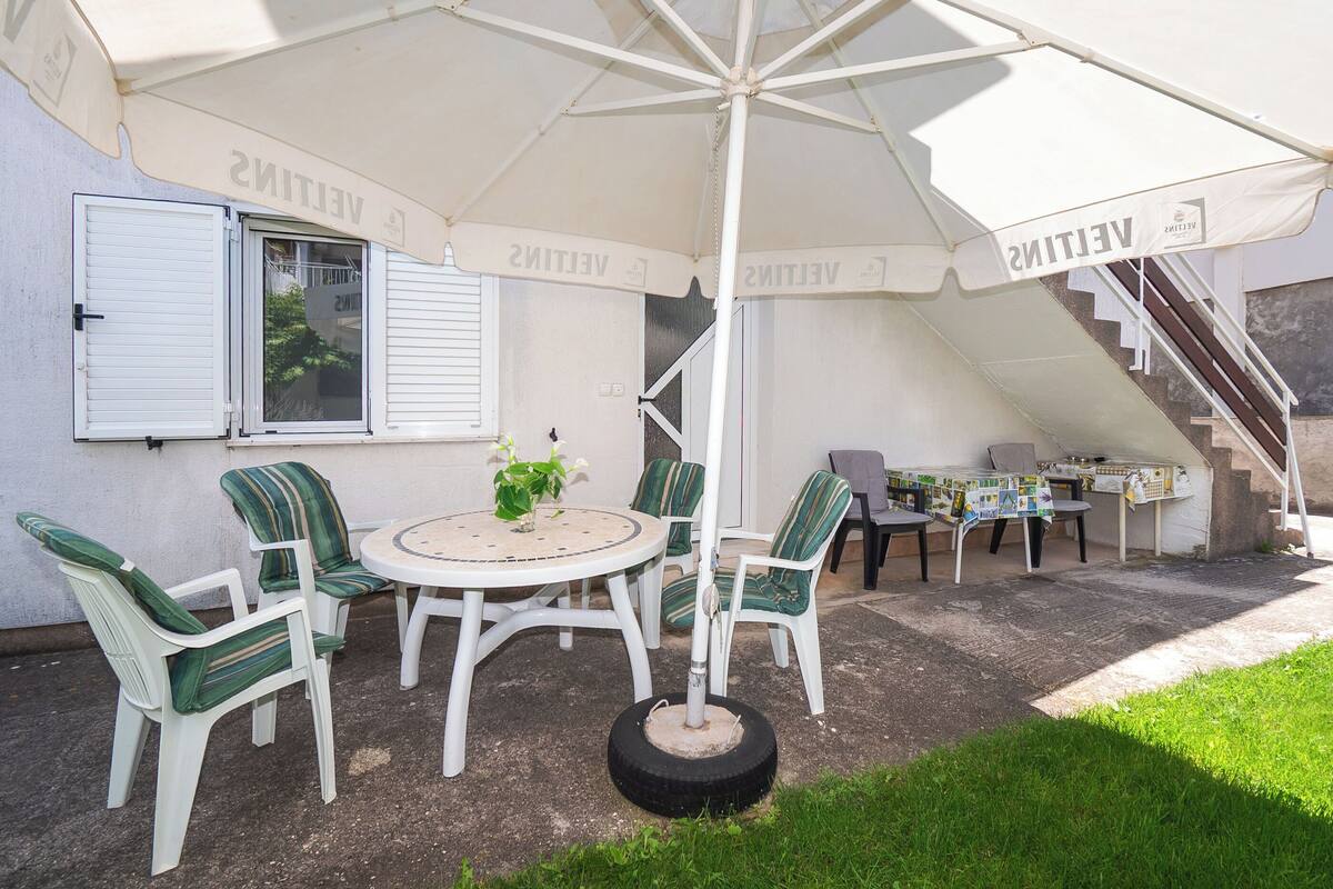 An outdoor patio with a round table, four chairs, and a large umbrella.