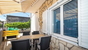 An outdoor patio with a stone wall, a wooden bench, and a table with chairs. - Apartments and Room Sanja (Vodice)