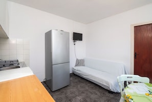 A compact kitchen with a refrigerator, a small dining table, and a sofa bed. - Apartments and Room Sanja (Vodice)