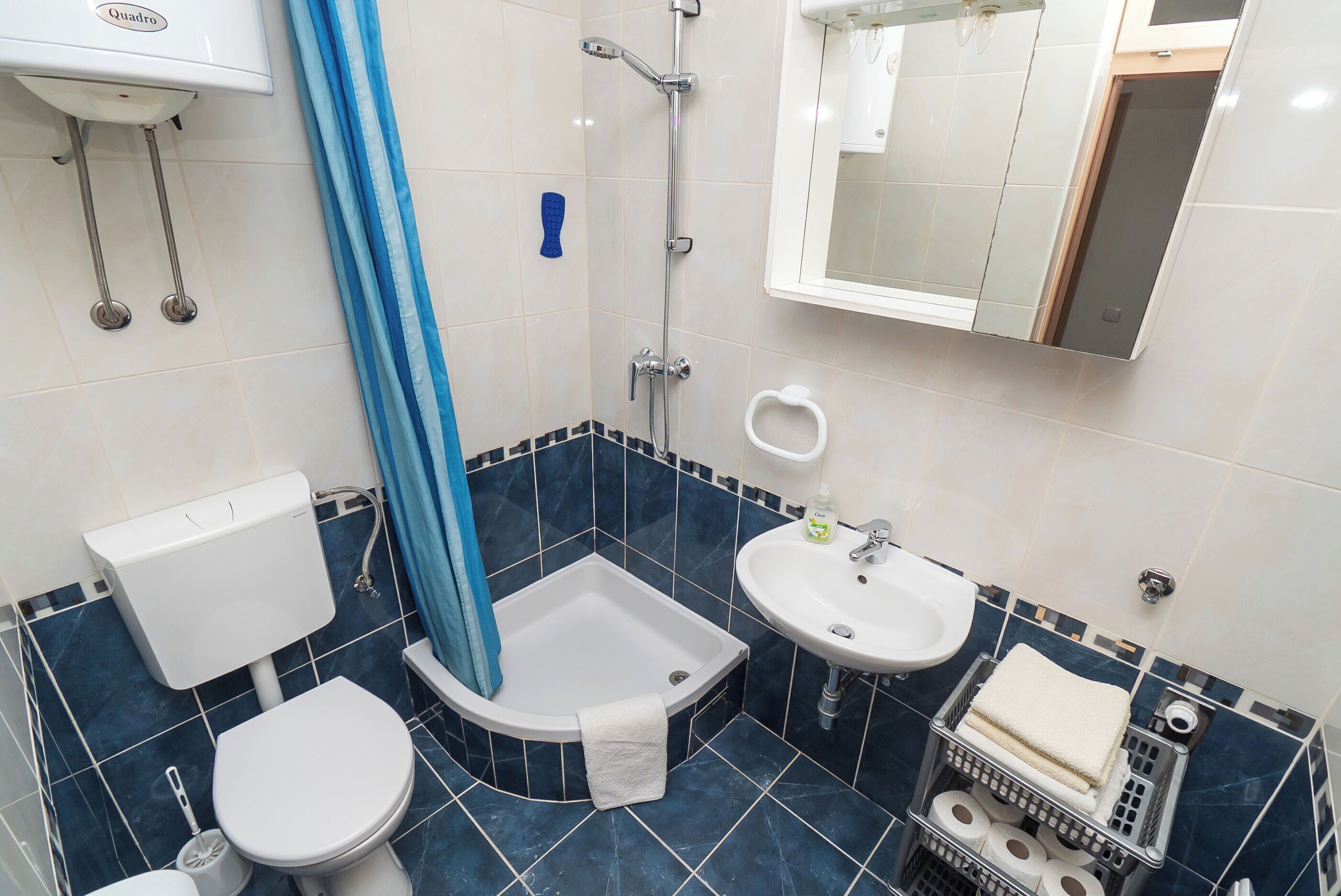 Ein Badezimmer mit Toilette, Dusche, Waschbecken und Spiegel.