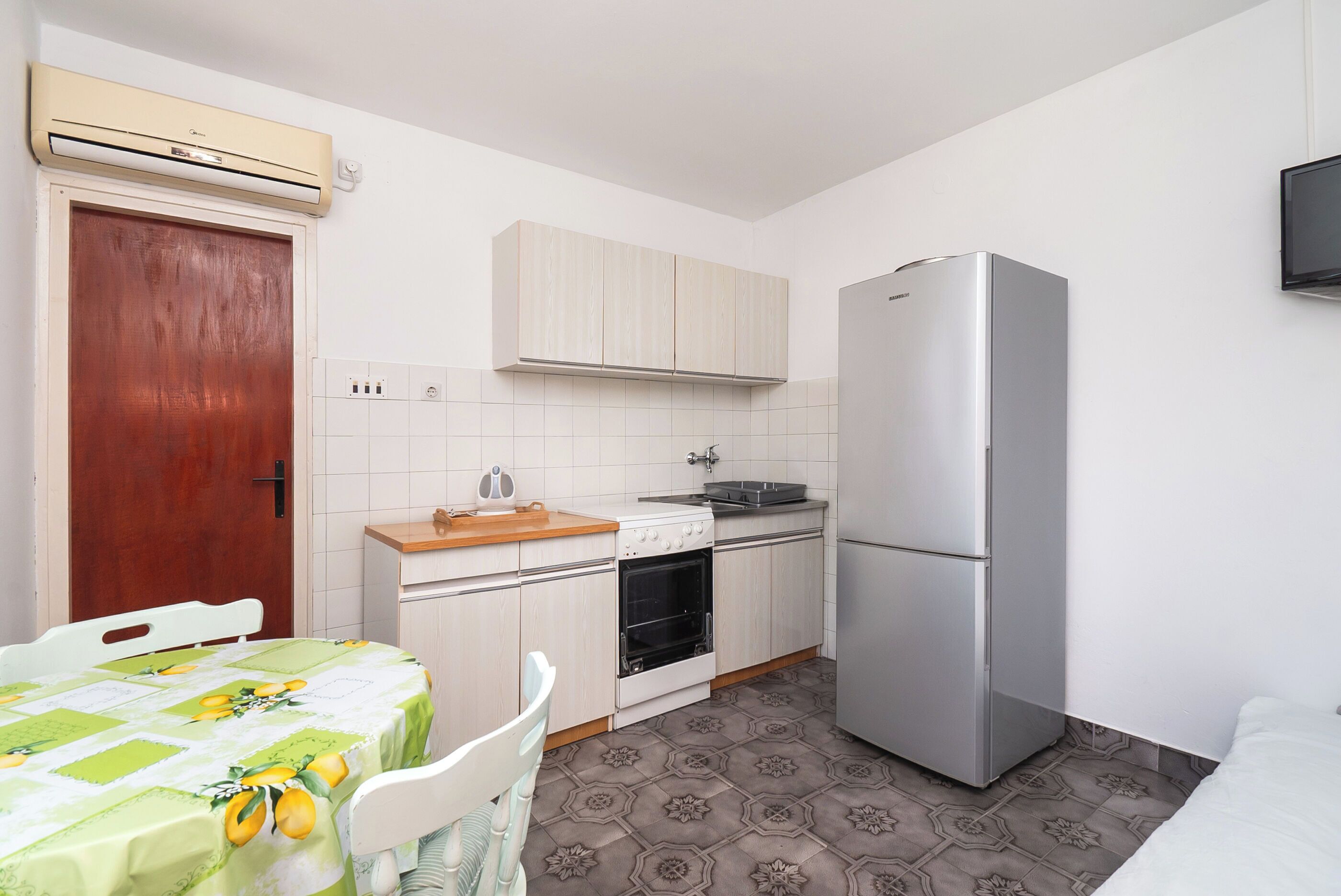 A compact kitchen with a refrigerator, oven, and a wooden countertop.